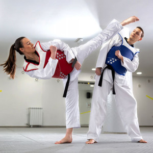 A young woman training taekwondo with her coach