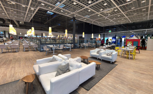 White cushioned seats with square shaped pillows, small, wooden living room tables and lots of pendant lamps hanging from the ceiling; all were displayed in IKEA Las Vegas Home Furnishing store's showroom