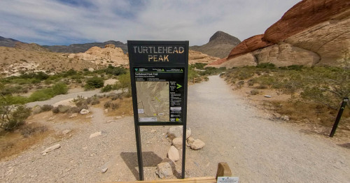 Las Vegas Turtlehead Peak signage standing at the start of the trail with the mountains & boulders on the background