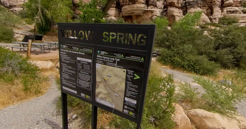 Mountain rocks, bushes and grasses surrounds a sign board at the start of the trail of Willow Spring Loop, Las Vegas