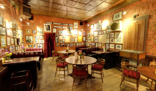 Wooden dining sets, cushioned couches & collection of old photos in a warm, vintage ambiance of the memorial room in Pioneer Saloon - a historical place in Nevada
