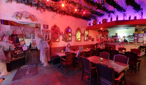 Las Vegas Mediterranean inspired interiors of a hookah bar in Vegas named The Olive Mediterranean Grill & Hookah Bar, beaming with red lights & a doorway to the gaming area with arcade machines