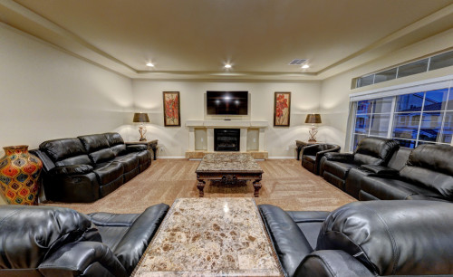 Sofa sets, stylish lamps & wall decors & a wooden center table facing the fire place inside the living room of one of the houses being sold by Shad Zaman, a Las Vegas Realtor