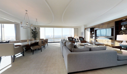 A spacious and elegant room in Trump International Hotel, Las Vegas complete with dining area & living room furnitures & a scenic view of the city through its huge, glass window