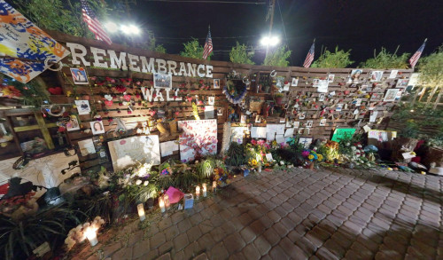 Las Vegas Community Healing Garden's remembrance wall showing pictures & memorabilia, decorated with flowers and lighted candles