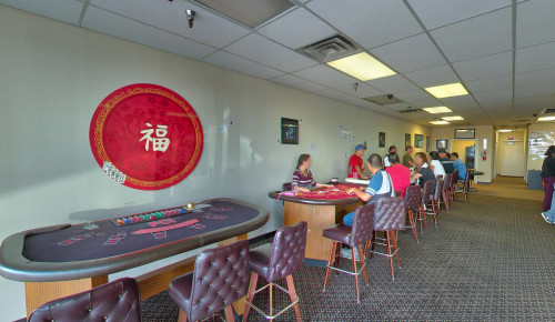 Front view of PCI Dealer School's building in Las Vegas with glass walls & students learning the skills in casino games