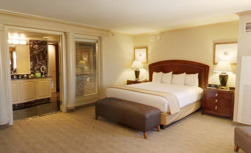 White, cream & brown interiors of a room in Harrah's Las Vegas Hotel & Casino, with warm lightings & comfortable bed