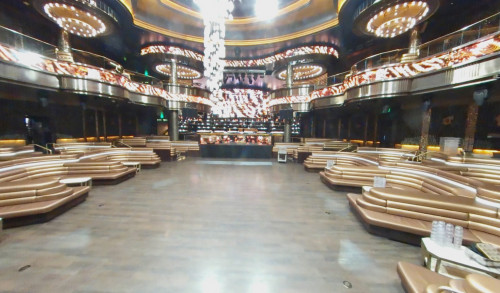 Omnia Night Club, Las Vegas' dancing hall surrounded with curved, gold colored sofas, sparkling lights from its iconic chandelier & DJ's booth at the center