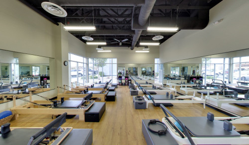 Several pilates machines, all aligned in a neat & well-lit studio of Core Pilates in Henderson, NV