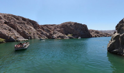 Las Vegas Enormous rock formations surround the blue waters of Lake Mead National Recreation Area in Boulder City, NV with a boat filled with tourists travelling the area